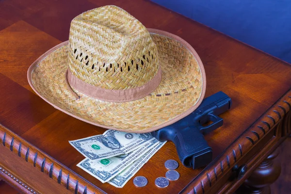 Hat, handgun and money on wooden desk