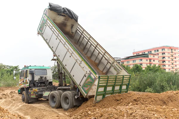 Dump truck dumps its load of rock and soil on land