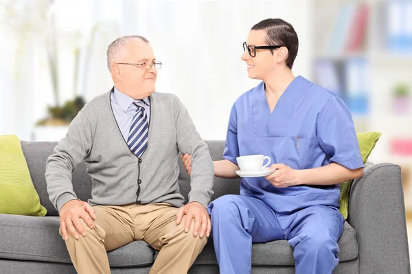 Senior and a male nurse on sofa