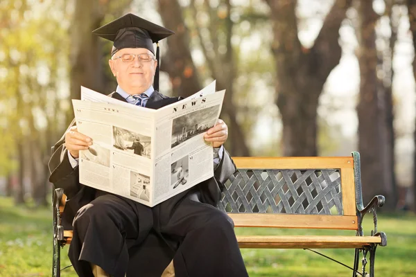 College professor reading newspaper in park