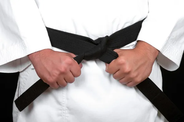 Karate man tying the knot to his black belt