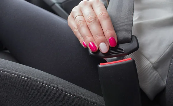 Woman fastening seat belt in car