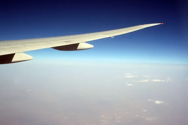 Wing of aircraft in blue sky.