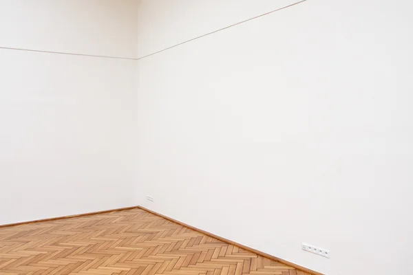 Corner of a large white wall with wooden floor tiles
