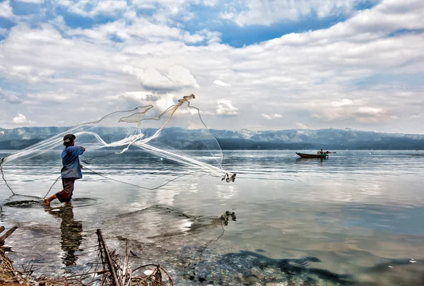 SUMATERA - FEBRUARY 10: A fisherman casts his net into Lake Singkarak, a tectonic lake in Sumatera, Indonesia on Feb 10, 2012. It is the biggest lake in Sumatera measuring 20km long and 8km wide.