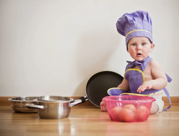 Baby-boy in a chief hat at the kitchen