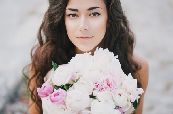 Beautiful girl with a bouquet of peonies