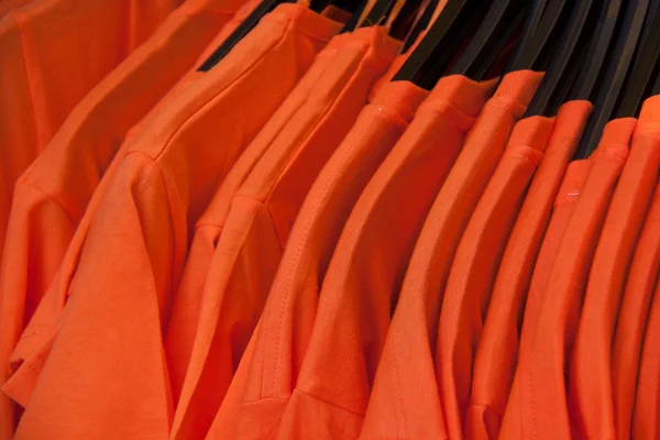 Closeup orange shirts adjacent to a clothes hanger
