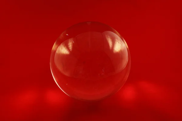 Glass sphere with light reflection and a red background