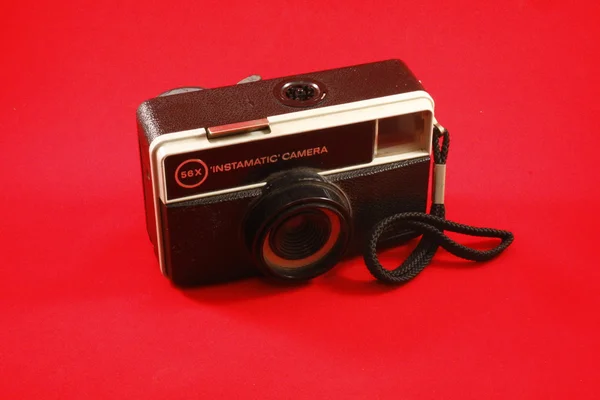Retro black photo camera with red background