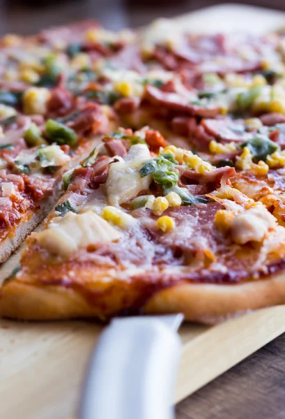 Cut on pieces pizza with sausage, chicken, corn and cheese