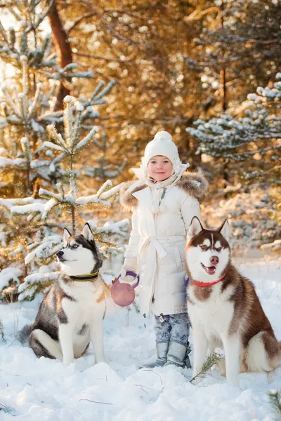 Beautiful little girl in winter forest with dog
