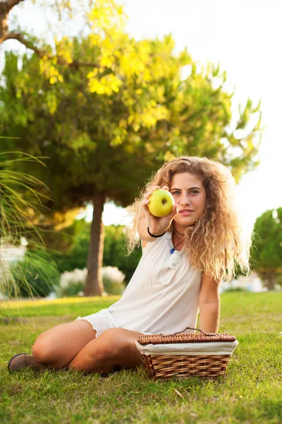 Woman showing apple at park