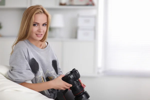Woman sitting on a sofa in her house with camera at home