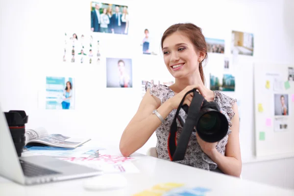 Young woman photographer processing pictures sitting on the desk