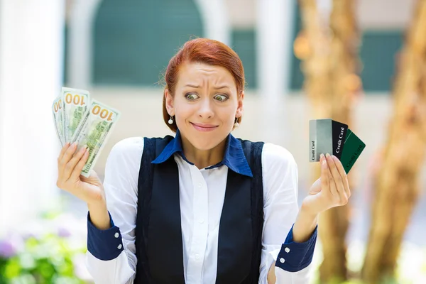 Confused woman holding credit cards and cash