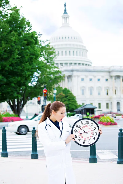 Health care professional holding wall clock on streets of Washin