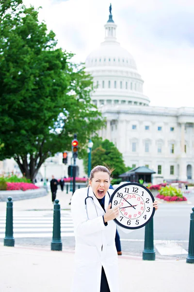 Health care professional holding wall clock on streets of Washin