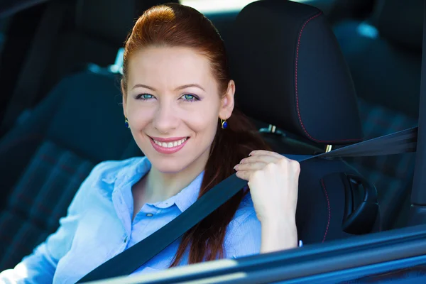 Woman pulling on seatbelt inside black car. Driving safety