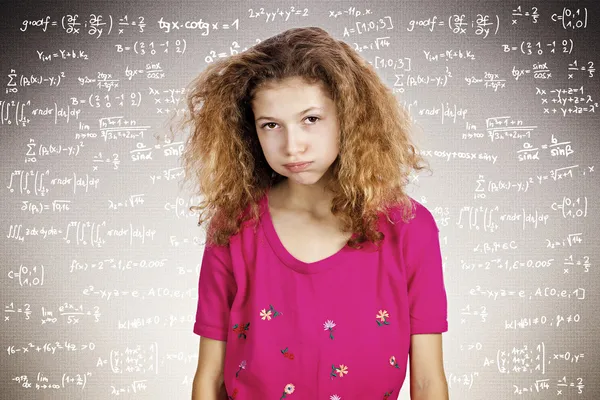 Stressed young student standing in front of a blackboard filled