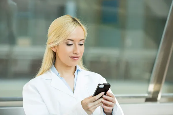 Happy female doctor texting on smart phone