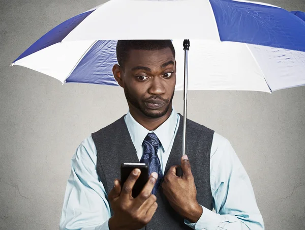 Executive man holding smart phone, reading news on a rainy day