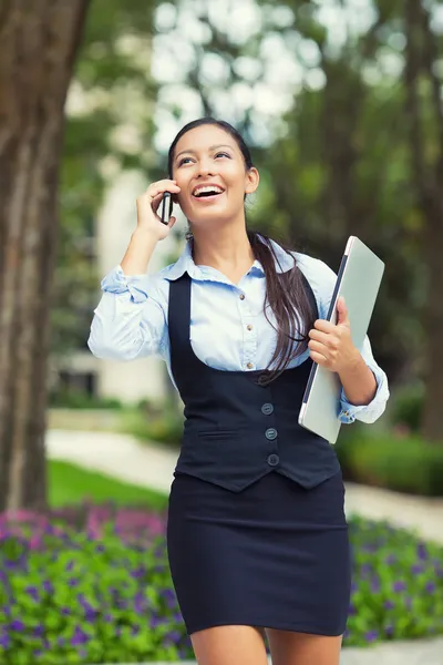 Happy busy business woman walking while talking on a smart phone