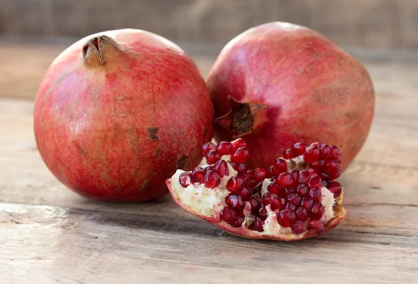 Red pomegranates on a plate on old wooden table