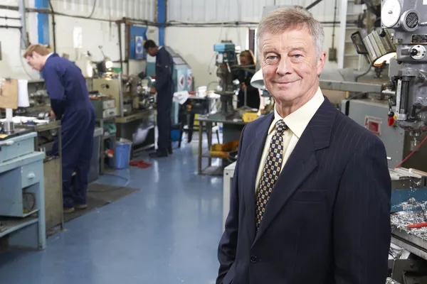 Owner Of Engineering Factory With Staff In Background