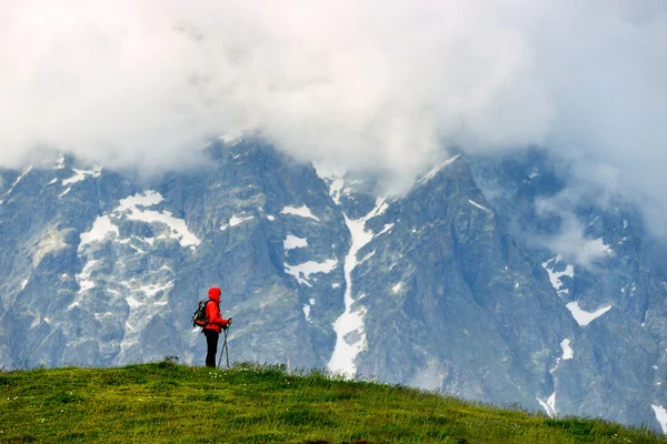 Young woman with backpack in red jacket in mountains