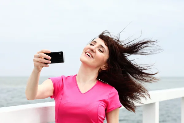 Woman showing on the beach display of her new touch mobile cell phone