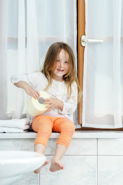 Cute little girl playing with toilet paper roll