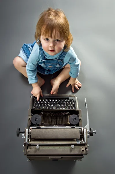 Cute little baby with retro style typewriter