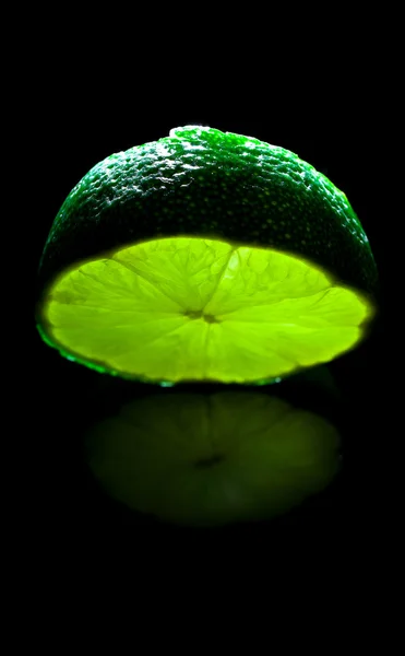 Bright green natural lime on black mirror background