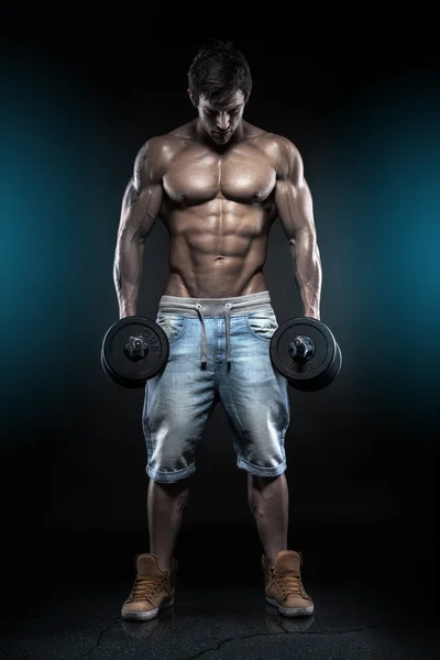 Muscular bodybuilder guy doing exercises with dumbbells over bla