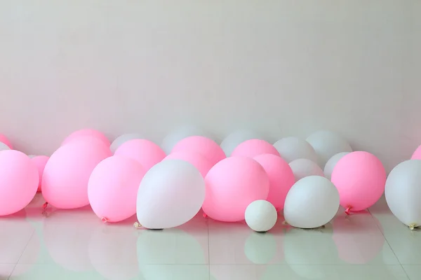 Pink and white balloon on floor with white wall background