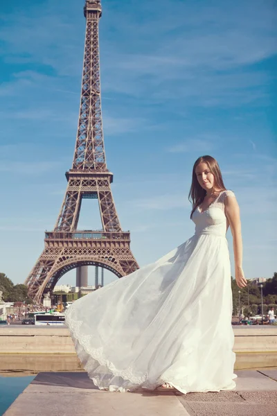 Vintage toned picture of a young bride in a white dress standing in front of the Eiffel Tower. Paris, France.