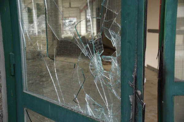 Broken glass door with green metal frame