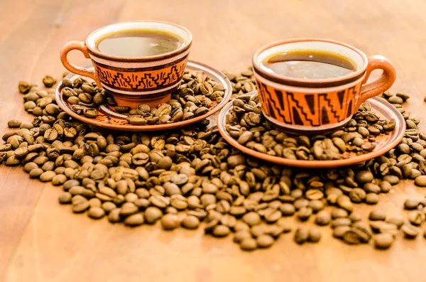 Coffee with steam, without steam, with coffee beans and rustic look on a wooden table. A set with a cup with coffee with coffee grain including cookies biscuit