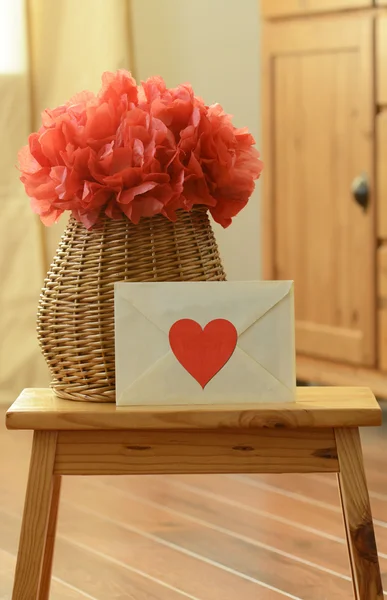 Vase basket with red tissue paper pom pom, and a love letter on the small wooden step stool