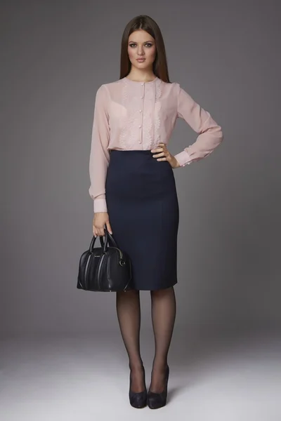 Beautiful sexy young business woman with evening make-up wearing a skirt to the knee and a silk blouse with lace long sleeves and high-heeled shoes, business clothes for meetings and walks