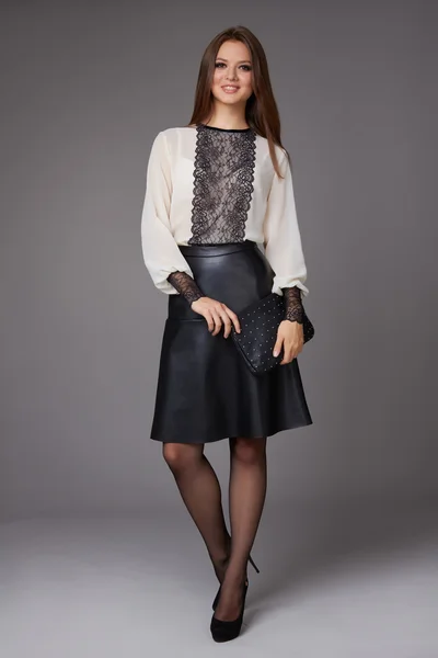 Beautiful business woman with evening make-up wearing a skirt to the knee a silk blouse with lace long sleeves and high-heeled shoes and a small black handbag, business clothes for meetings and walks
