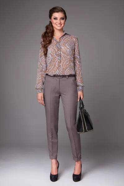 Beautiful sexy young business woman with evening make-up dressed in tight pants and silk blouse with lace long sleeves and high-heeled shoes and a small black handbag, business clothes meetings walks