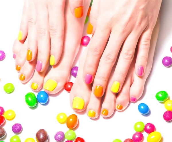 Woman hands with manicure and feet with pedicure and bright candies around