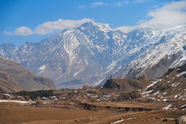Bir dağ vadisinde, arka planda dev kaplı dağların nefes kesici manzarası.