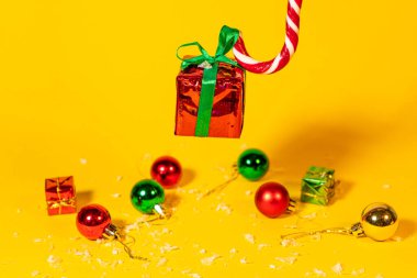 Şeker kamışı lolipop, sarı arka planda Noel hediyesi olan bir hediye kutusu, yeni yıl süslemeleri olan Noel şekerlemeleri..