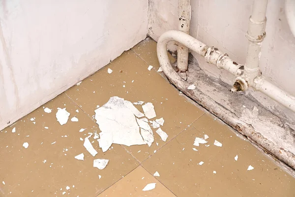 房子的内部是一座需要整修的旧房子 墙上的碎屑白色石膏躺在地板上 靠近旧的散热器 — 图库照片