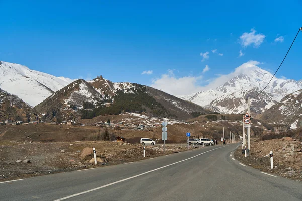 Kazbegi Dağı 'nın aşağısına giden otomobil dağ yolu. Dağın tepesinde kar şapkası.