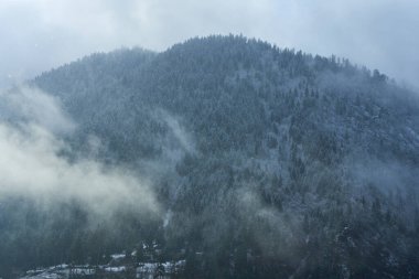 Kış dağı manzarası. Dağlar arasında küçük bir kasaba. Şehrin üzerinde bir bulut asılı..