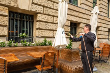 Restoran personeli restoranın yaz terasında çiçekleri suluyor. Berlin, Almanya - 05.17.2019